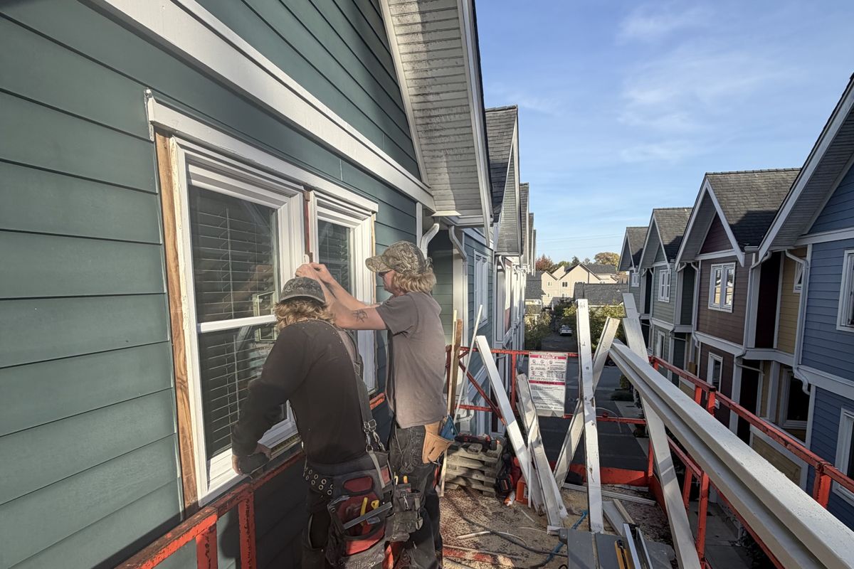 Two Husband Contracting crew members installing window trim from a scaffold