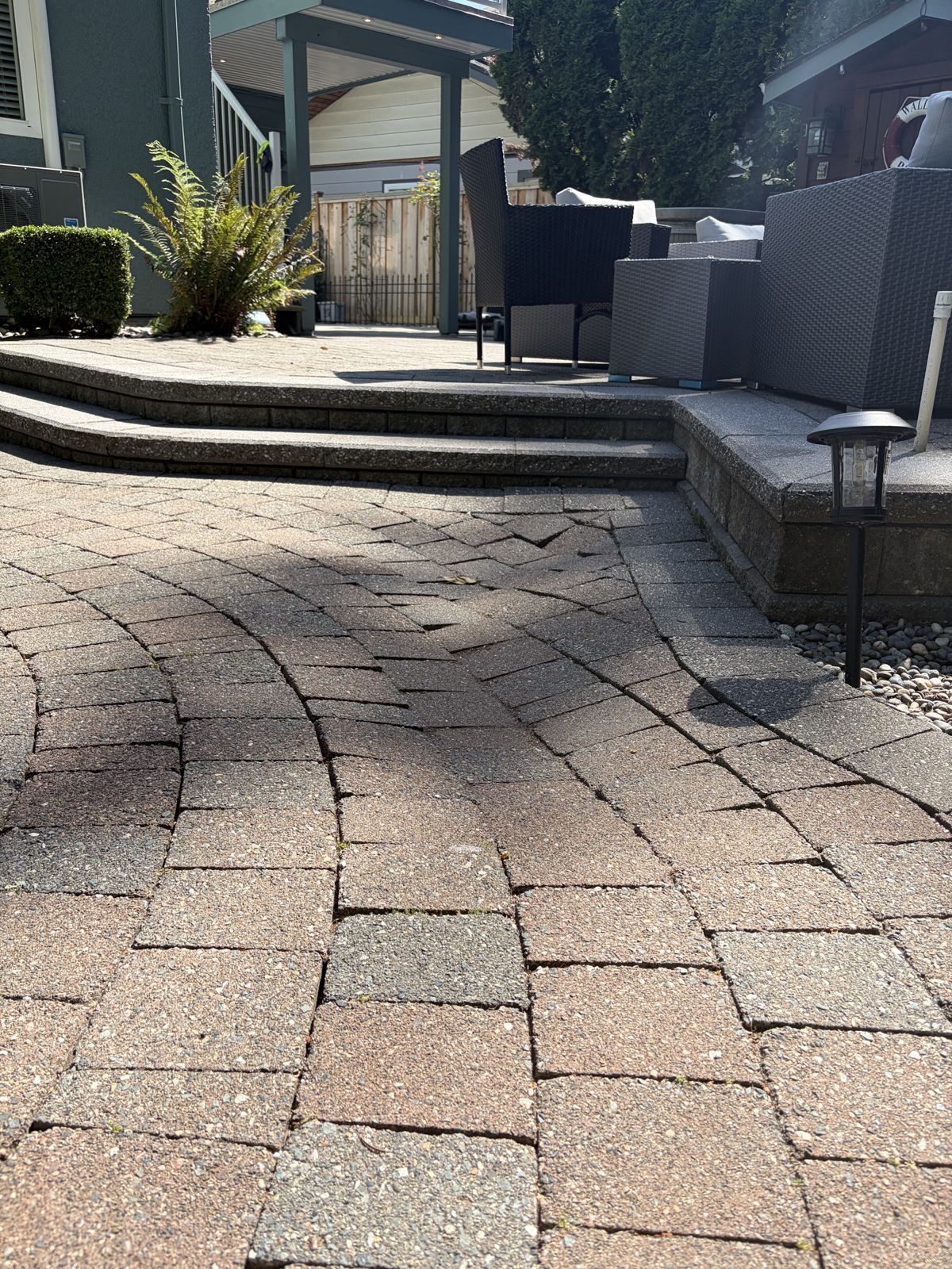 Curved paver patio with stone steps up to an outdoor seating area