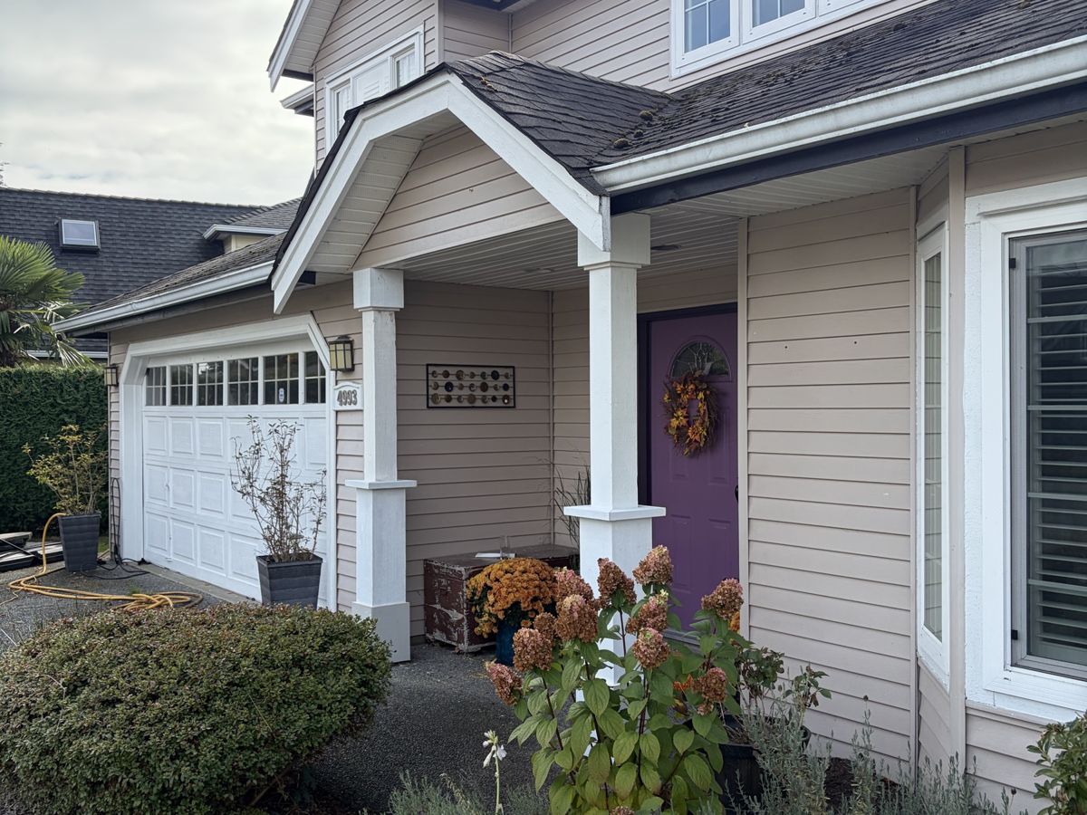 Refreshed front entry with white columns, purple door and fall planters